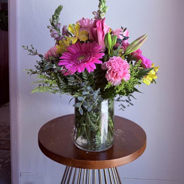 Mixed bouquet of pink and yellow flowers in a clear glass vase