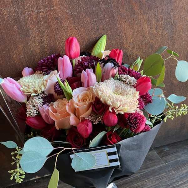 Bouquet of pink tulips, roses, and chrysanthemums wrapped in black paper