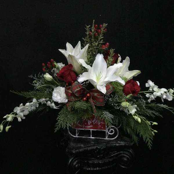 Holiday floral arrangement with white lilies, red roses, and a plaid ribbon