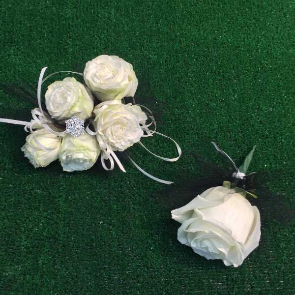 White rose corsage and matching boutonniere on green grass