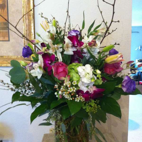 Mixed bouquet of pink, purple, white, and green flowers in a glass vase
