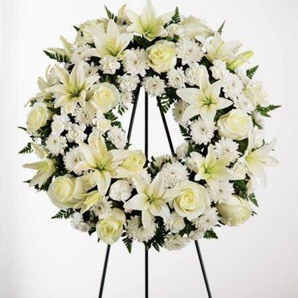 White floral wreath on a black easel stand