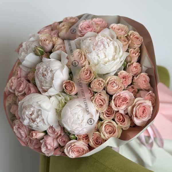 Bouquet of pale pink roses and white peonies wrapped in paper