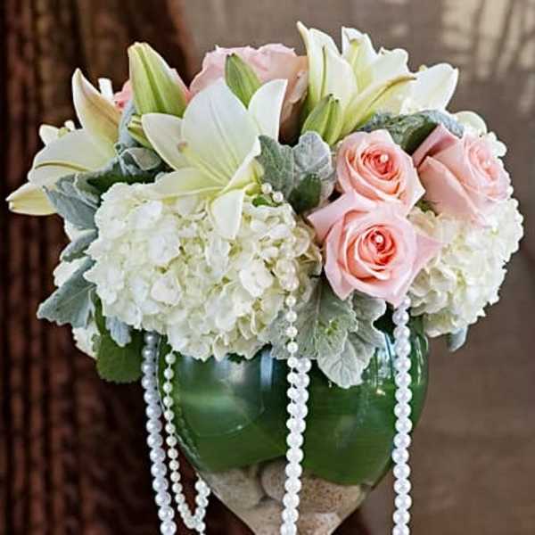 Bouquet of white lilies, pink roses, and white hydrangeas in a green vase