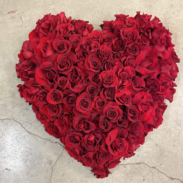 Heart-shaped arrangement of red roses on a stone surface