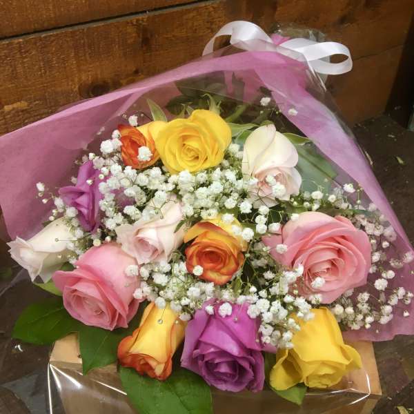 Bouquet of multicolored roses with baby's breath in pink wrap