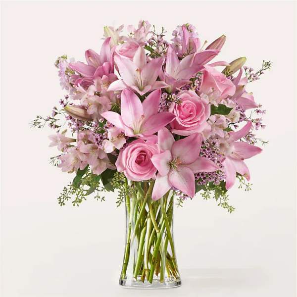 Pink lilies and roses arranged in a clear glass vase
