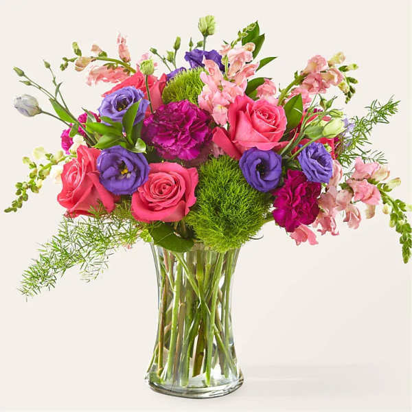 Mixed pink, purple, and white flowers arranged in a clear glass vase