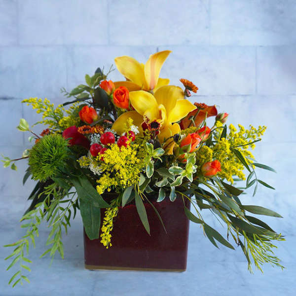 Yellow lilies and orange roses in a burgundy vase