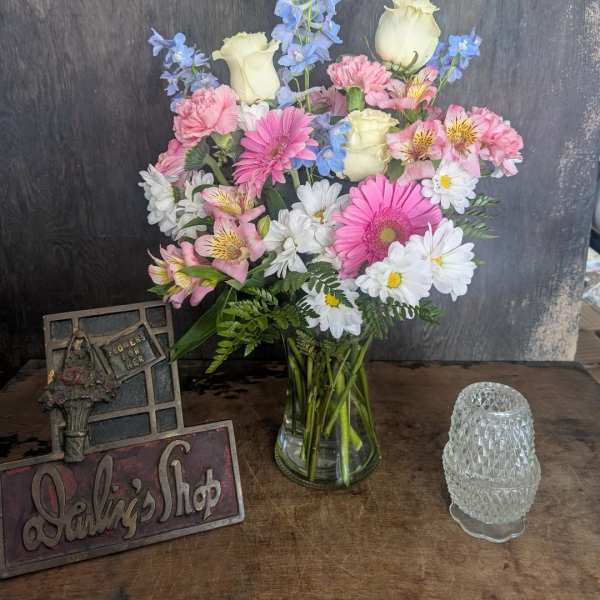 Mixed bouquet in a clear glass vase with pink, white, and blue flowers