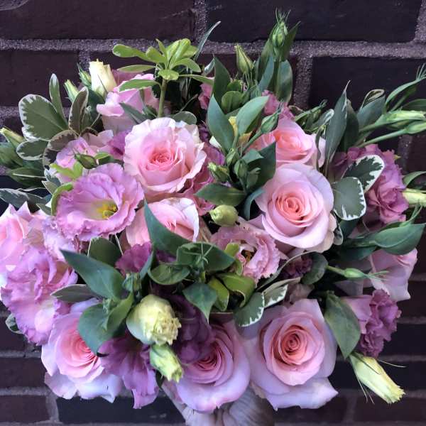 Pink roses and lisianthus bouquet with green foliage