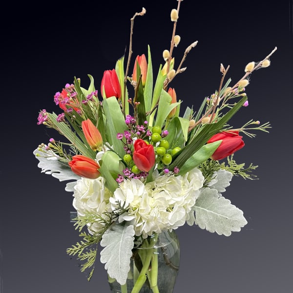 Bouquet of red tulips and white hydrangeas in a glass vase