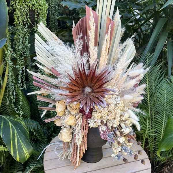 Dried floral arrangement with fan-shaped leaves and pampas grass in a dark vase