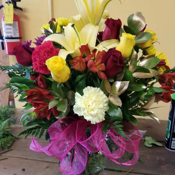 Mixed bouquet of lilies, roses, carnations, and alstroemeria in a glass vase