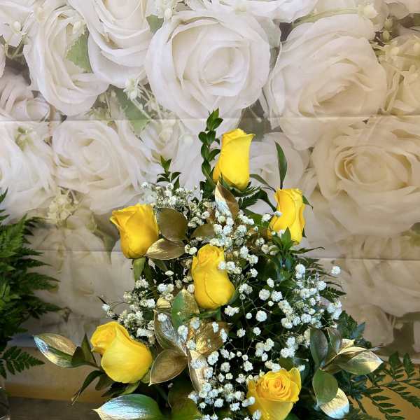 Yellow roses with baby's breath in a clear vase with a white ribbon