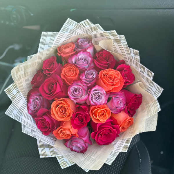 Bouquet of pink, orange, and lavender roses wrapped in patterned paper