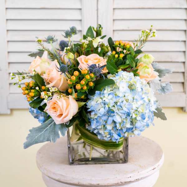 Bouquet of peach roses and blue hydrangeas in a glass vase