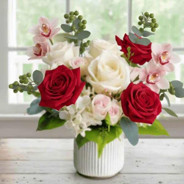Red and white roses with pink orchids in a white vase