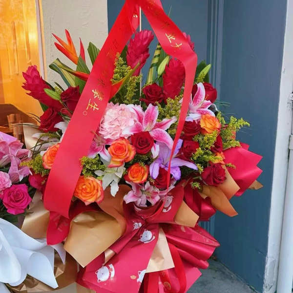 Large bouquet of red, pink, and orange flowers with a red ribbon