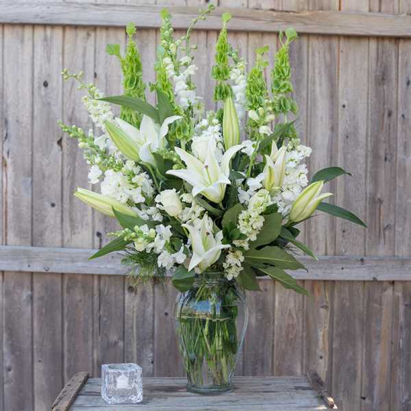 White lilies and snapdragons arranged in a clear glass vase