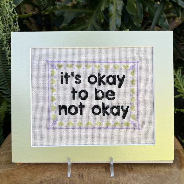 Framed cross-stitch sign with the words "it's okay to be not okay"