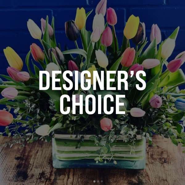 Mixed tulips arranged in a rectangular glass vase with greenery