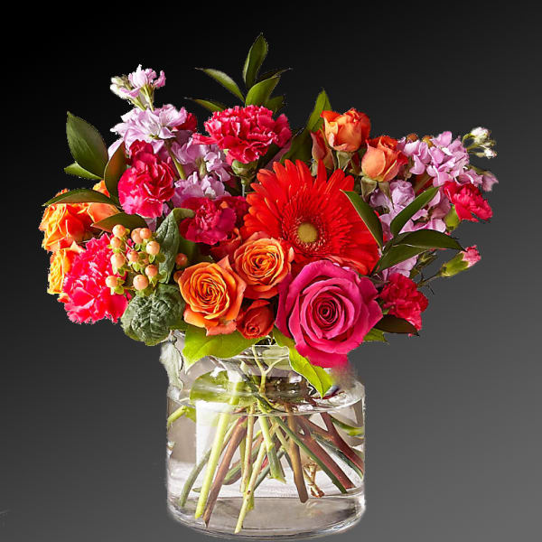 Mixed bouquet of roses, gerbera daisies, and carnations in a glass vase