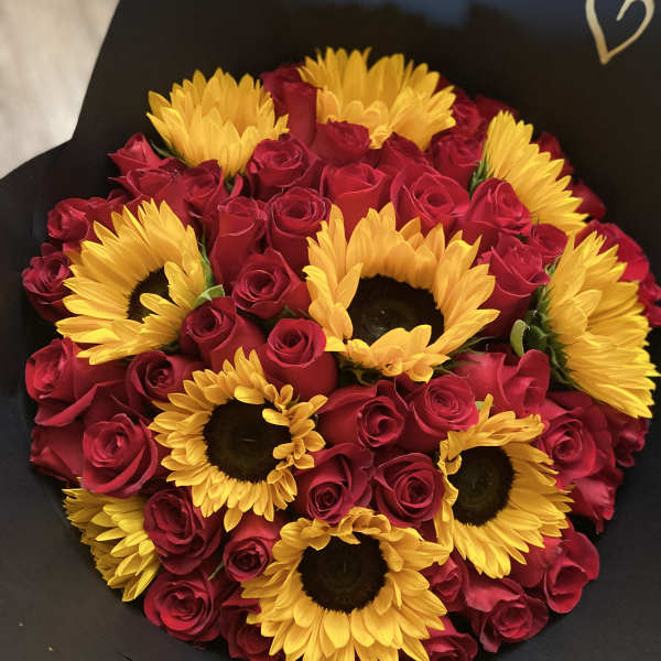 Bouquet of red roses and yellow sunflowers wrapped in black paper