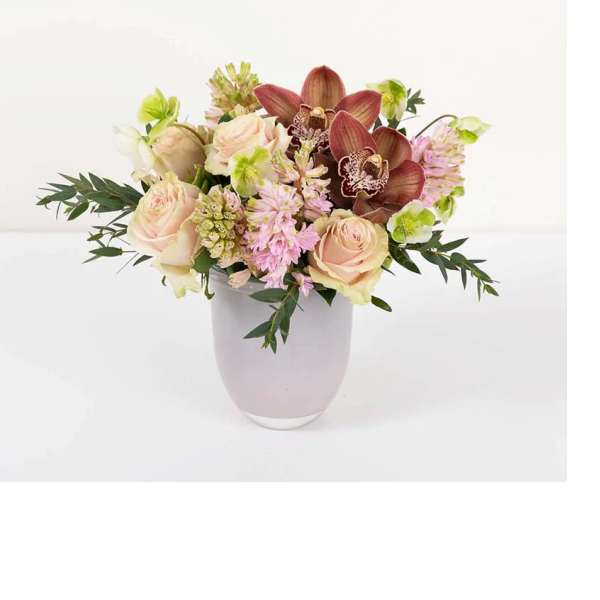 Pink roses and orchids arranged in a pale vase
