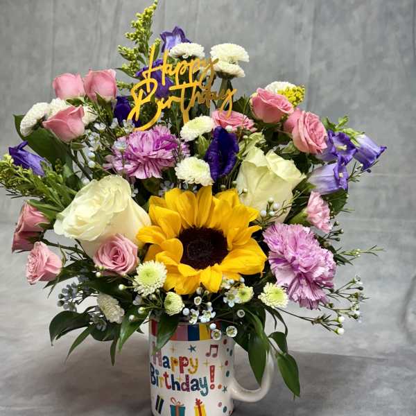 Birthday bouquet in a mug with sunflowers, roses, and mixed blooms