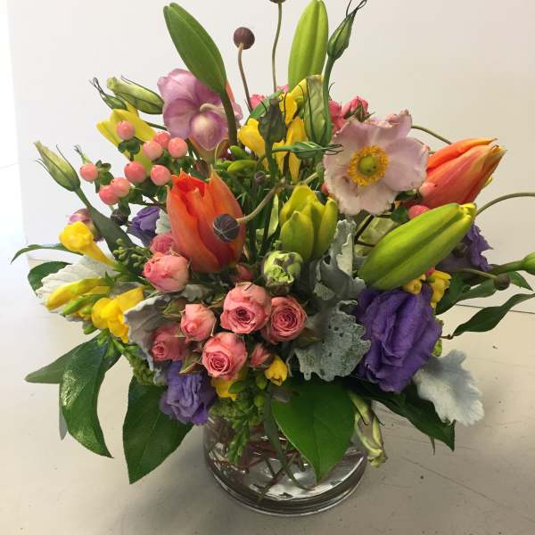 Colorful mixed bouquet in a clear glass vase with tulips and roses