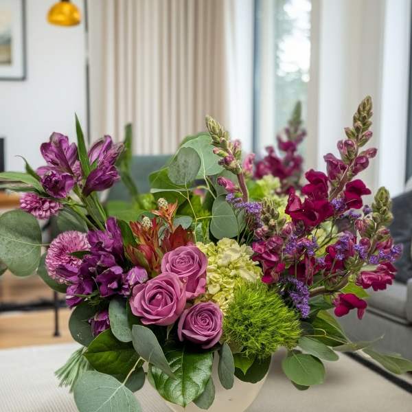 Purple and pink floral arrangement in a white vase
