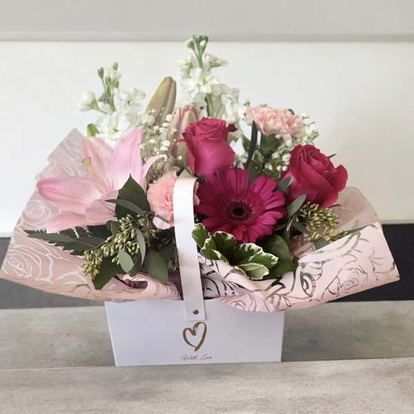 Pink and white mixed flower arrangement in a white box