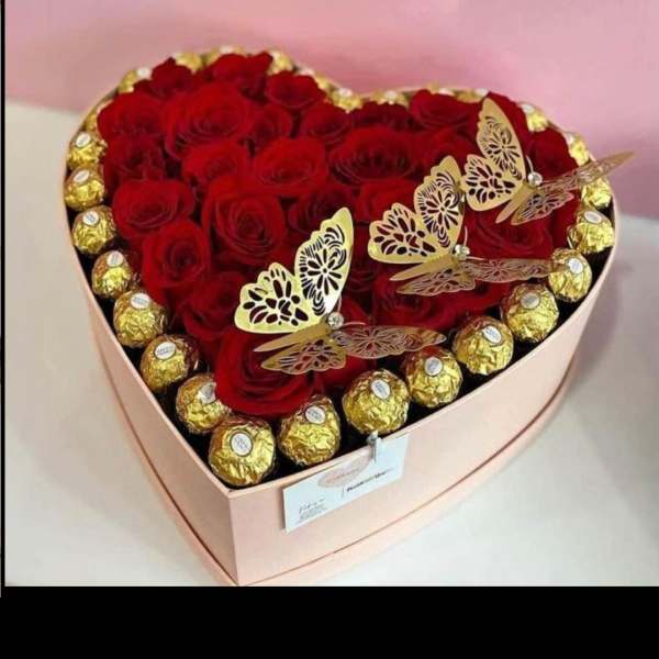 Heart-shaped box of red roses with gold-wrapped chocolates and butterfly decorations