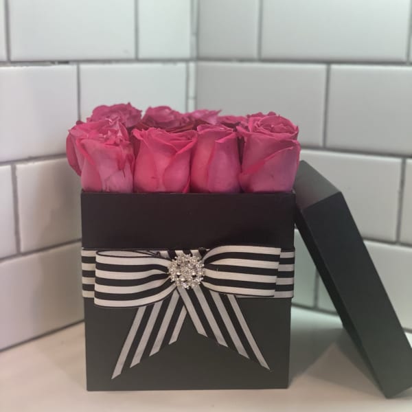 Pink roses in a black gift box with a striped ribbon