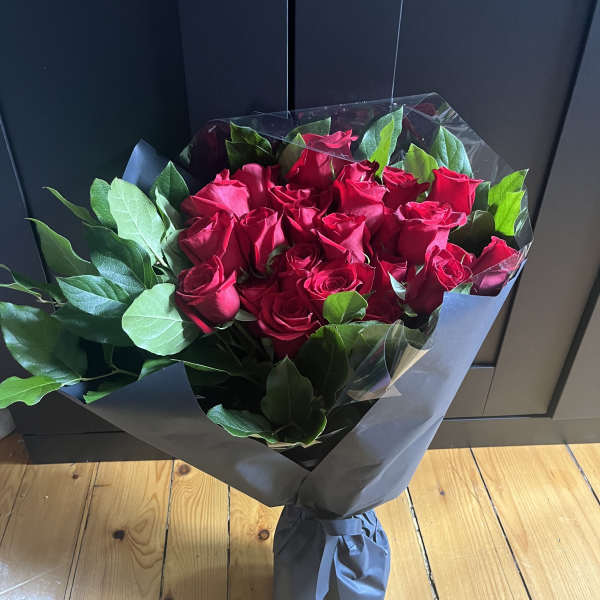 Bouquet of red roses wrapped in dark paper