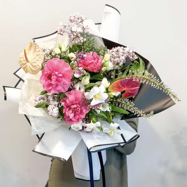 Hand-tied bouquet with pink blooms, white flowers, and an anthurium accent