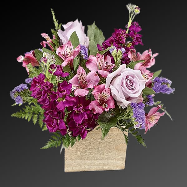Pink and purple mixed flower arrangement in a beige vase