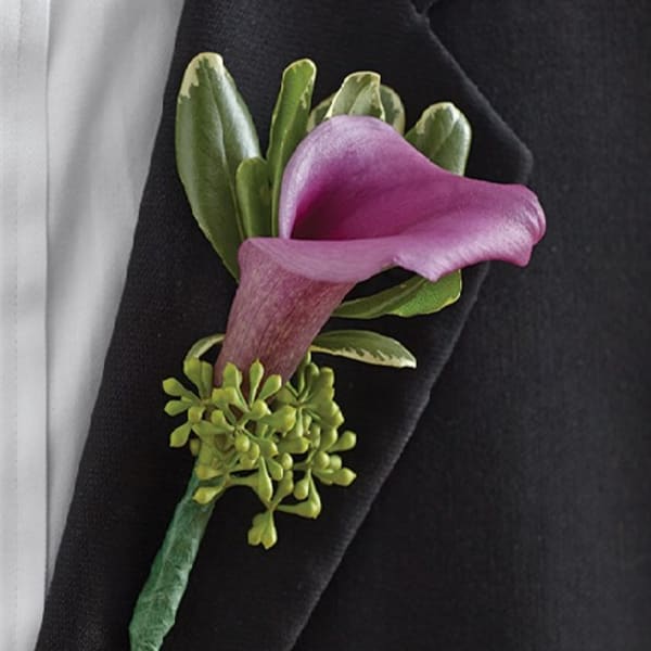 Purple calla lily boutonniere with green accents on a black lapel