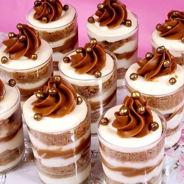 Dessert cups topped with caramel frosting and gold sprinkles