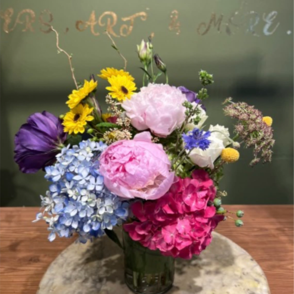 Mixed bouquet with hydrangeas, peonies, and daisies in a glass vase