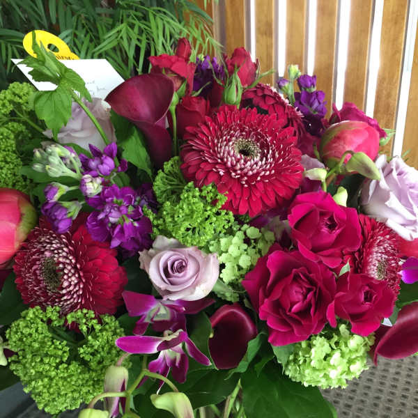 Mixed bouquet of pink, purple, and green flowers in a glass vase