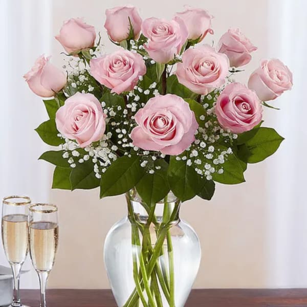 Pink roses arranged in a clear glass vase with baby's breath