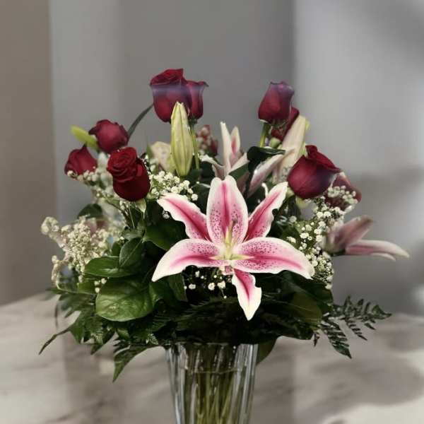 Pink lilies and red roses in a clear glass vase