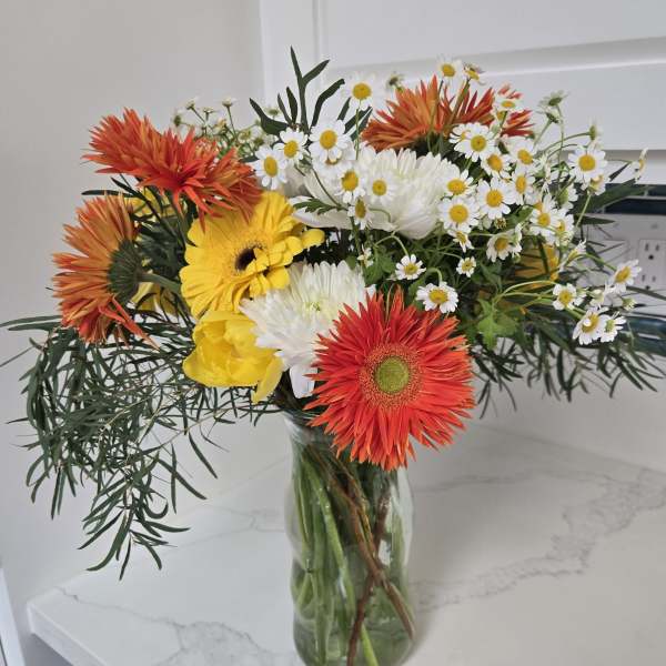 Bouquet of orange, yellow, and white flowers in a glass vase