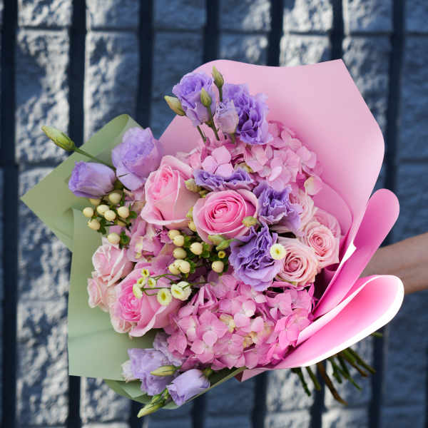 Bouquet of pink and lavender flowers wrapped in pastel paper