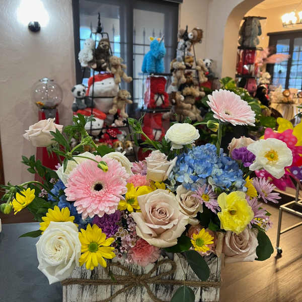 Mixed bouquet in a rustic wooden box with roses, gerbera daisies, hydrangea, and ranunculus