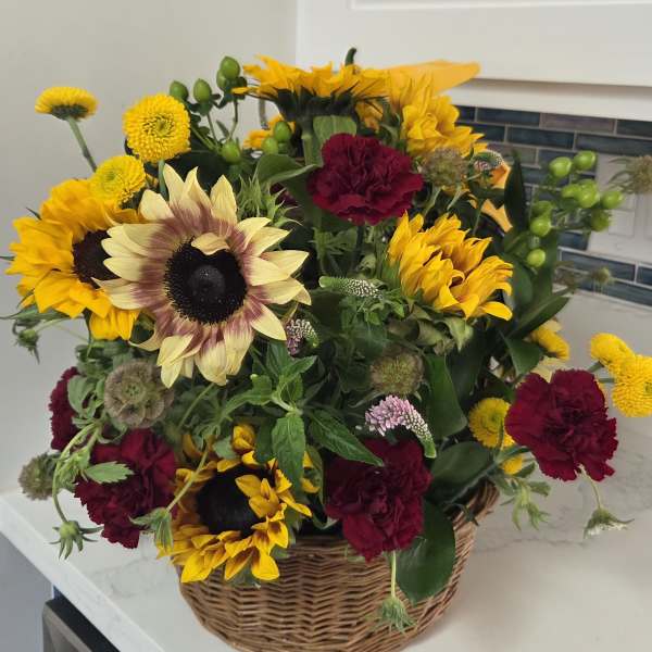 Basket arrangement of sunflowers and burgundy carnations