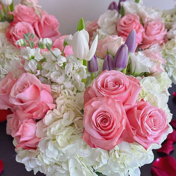 Pink roses and white hydrangeas with purple tulips in a glass vase