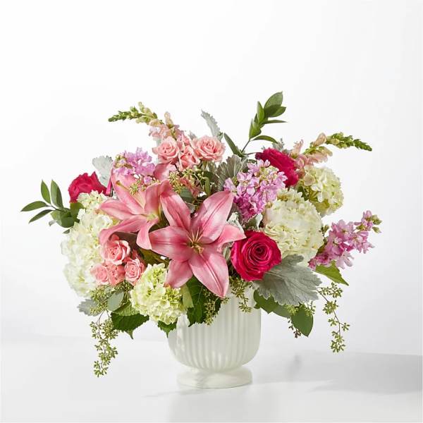 Pink lilies and roses in a white vase with white hydrangeas